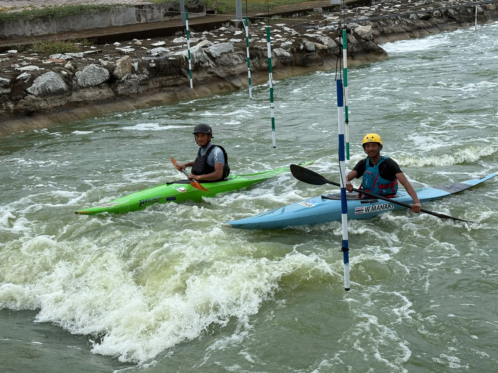 Kayakers training on an artificial whitewater course at a canoe slalom training camp in Thailand