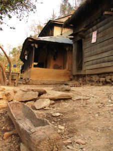 Magar family homestead beside the Trisuli River with a dugout canoe in the foreground, Nepal