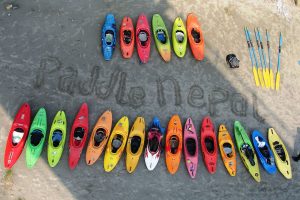Paddle Nepal's name carved into the sand and encircled by colorful kayaks at the company's operations base.